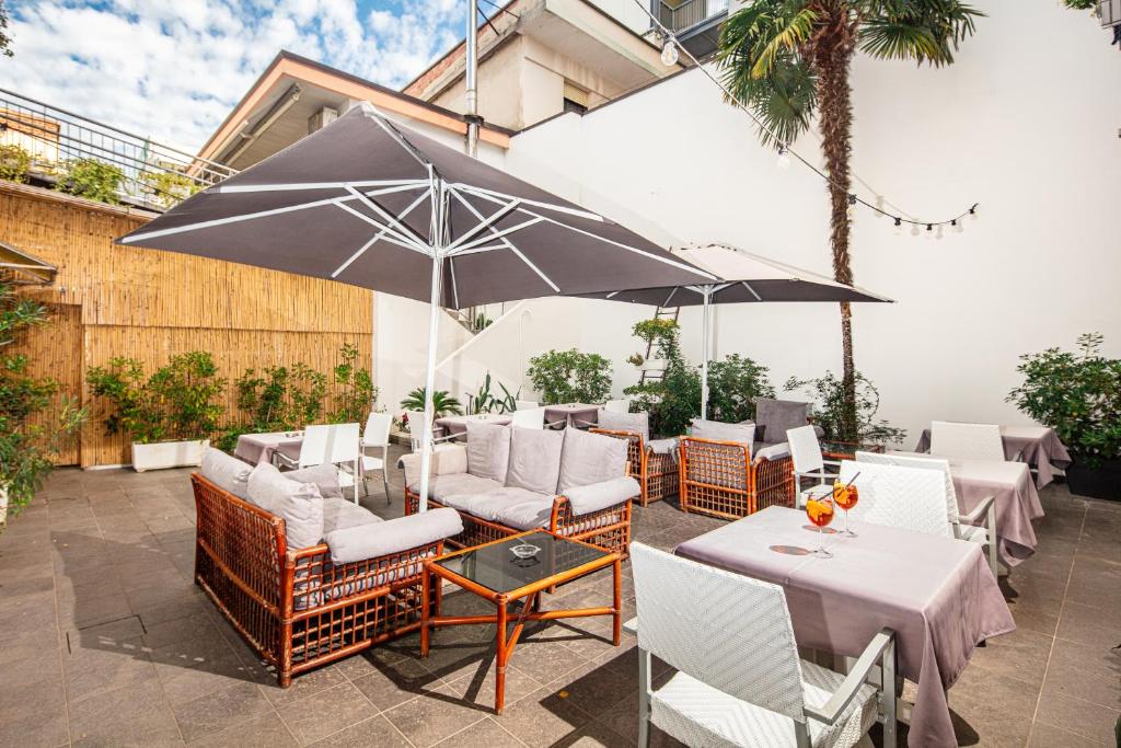un patio avec tables, chaises et un parasol dans l'établissement Hotel Centrale, à Lignano Sabbiadoro