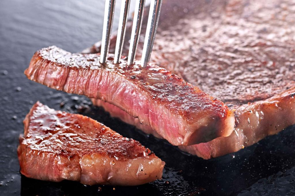 un morceau de viande avec une fourchette dessus dans l'établissement Ooedo Onsen Monogatari Premium Shirahama Saichoraku, à Shirahama