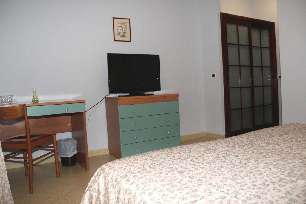une chambre avec un lit, un bureau et une télévision dans l'établissement Hotel Geranio Rosso, à Stintino