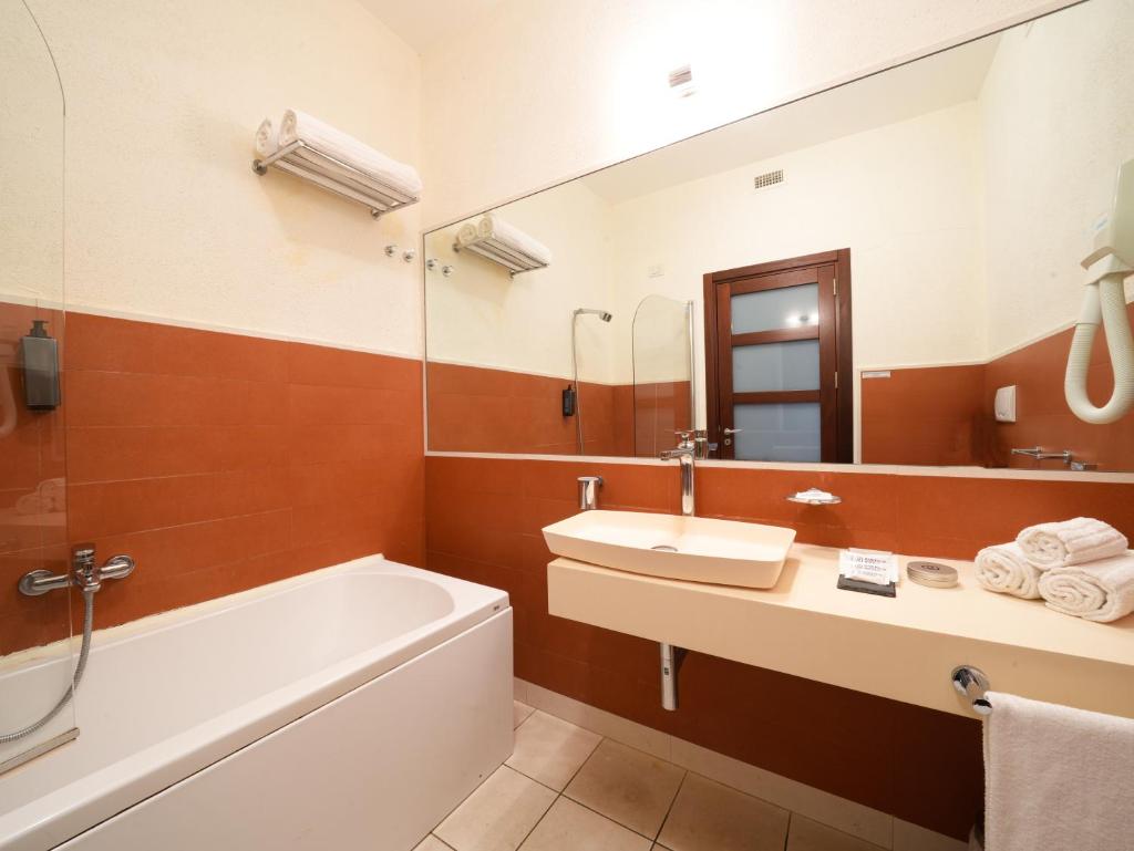 une salle de bain avec une baignoire, un lavabo et un miroir dans l'établissement GH Gallipoli Resort, à Gallipoli