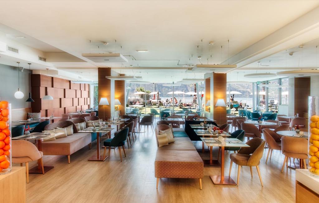 un restaurant avec des tables et des chaises et une grande fenêtre dans l'établissement Hotel Castello Lake Front, à Malcesine