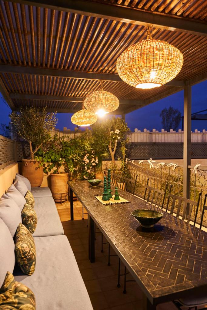 un patio avec une longue table en bois et des lustres dans l'établissement Riad Algora en exclusivité 13 P au cœur de la Médina, à Marrakech
