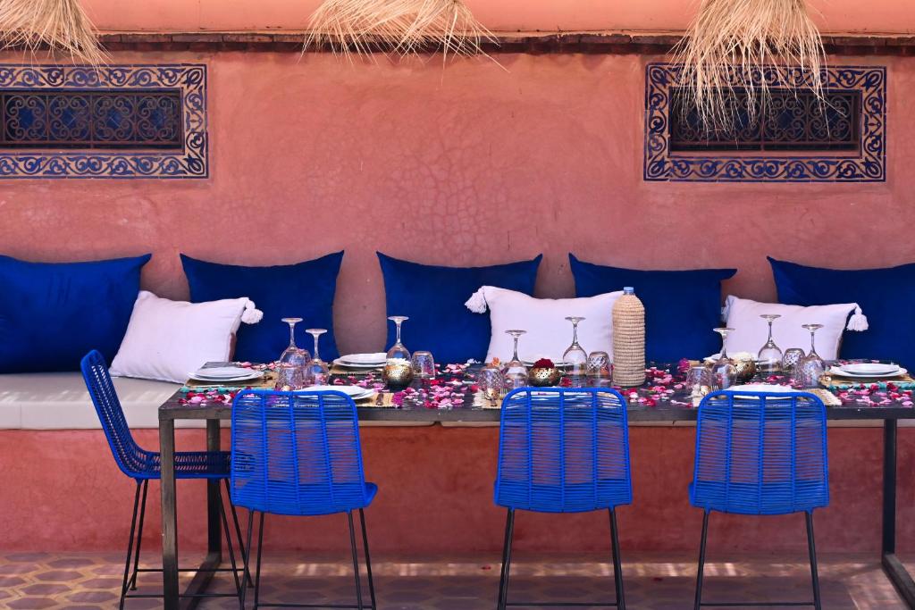 une table avec des chaises bleues devant un mur dans l'établissement La Casa Ysabella, à Marrakech