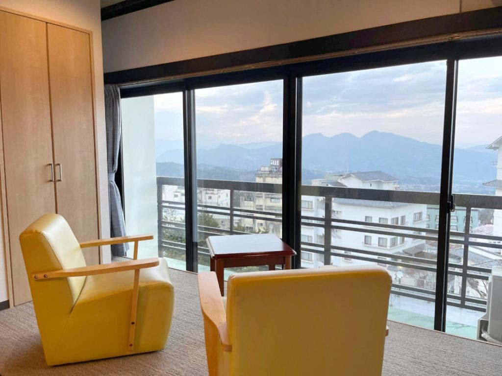 un salon avec deux chaises et une grande fenêtre dans l'établissement Kindayu, à Shibukawa
