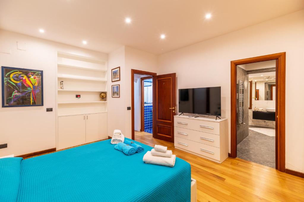 une chambre avec un lit bleu et une télévision à écran plat dans l'établissement Aqua Suites Doria, à Syracuse