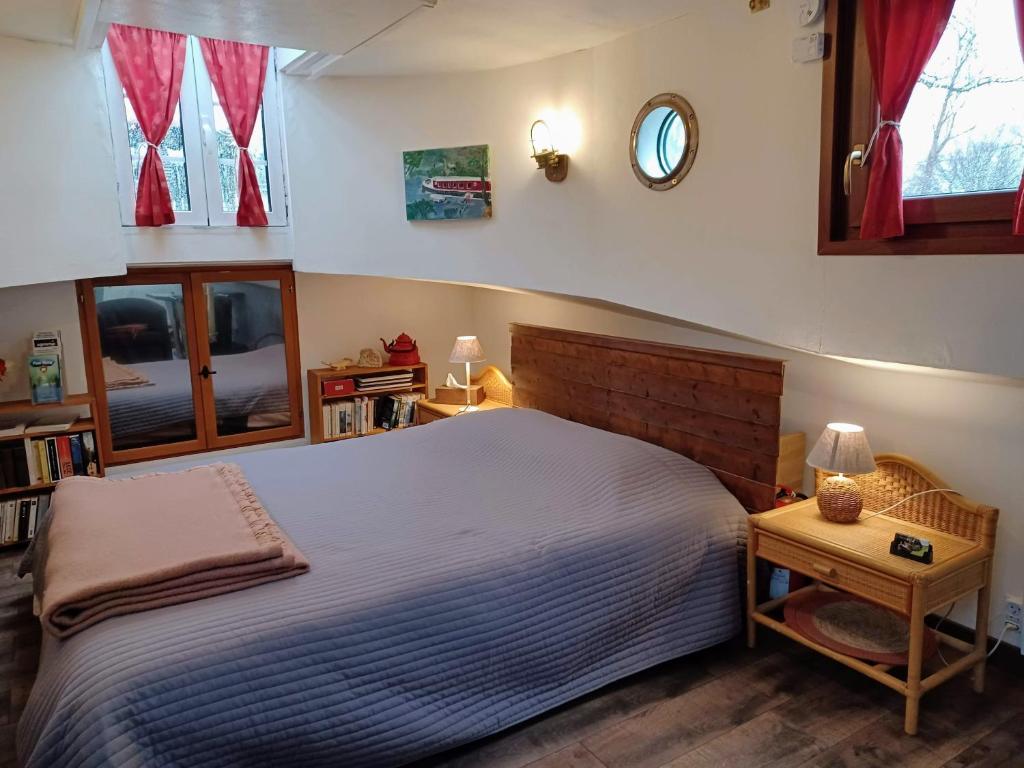 une chambre avec un lit et une horloge au mur dans l'établissement Sur la Somme à bord de la péniche Arche de Noé, à Pont-Rémy