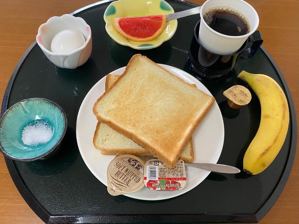 un plateau noir avec une assiette de pain grillé et une tasse de café dans l'établissement 熱海来宮の湯 松月, à Atami