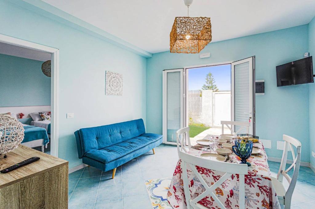 un salon avec une table et un canapé bleu dans l'établissement Villa Arancio by Villa Plus, à Santa Maria Del Focallo