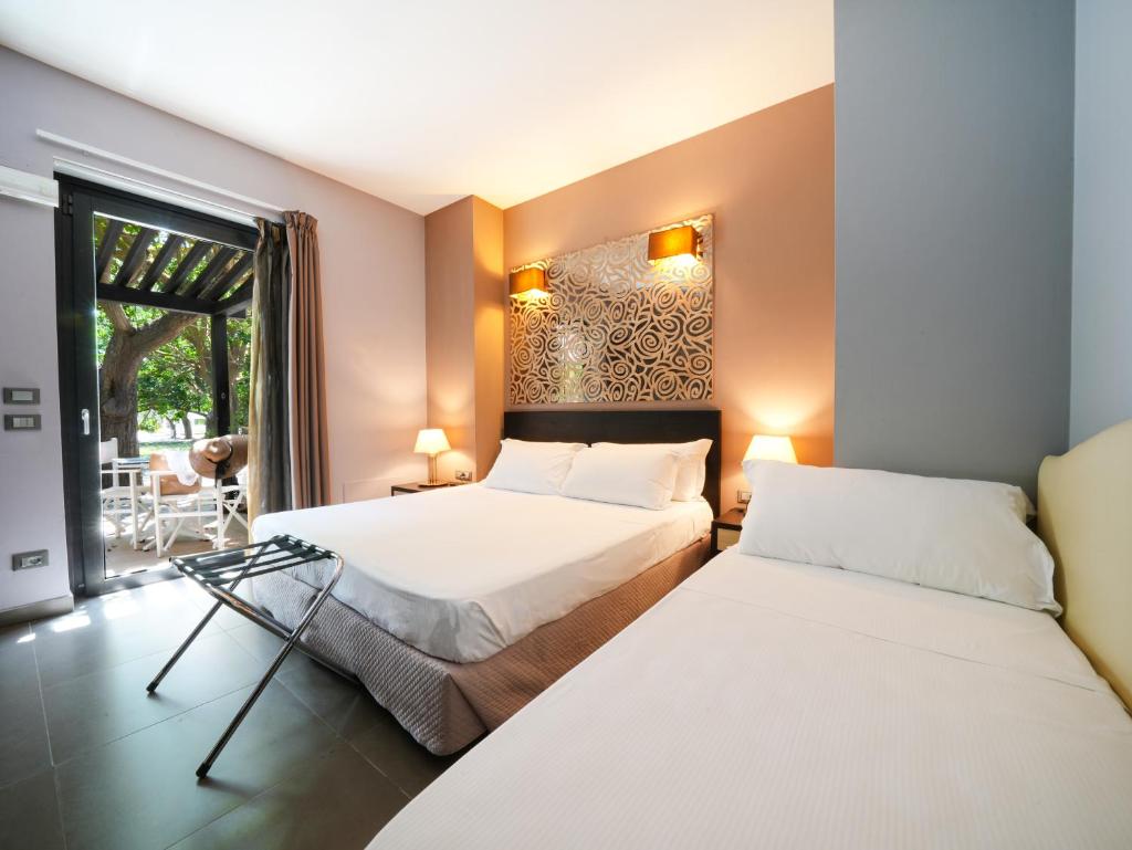 deux lits dans une chambre avec une fenêtre dans l'établissement Le Dune Resort, à Menfi