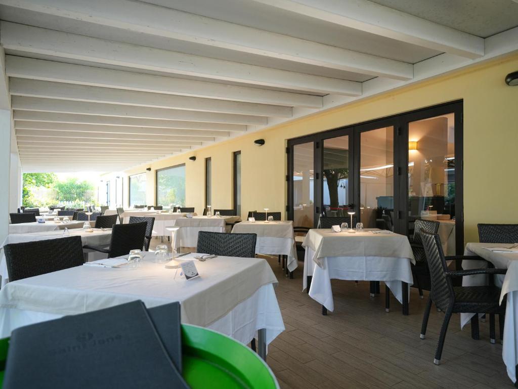 un restaurant avec des tables et des chaises blanches et des fenêtres dans l'établissement Le Dune Resort, à Menfi