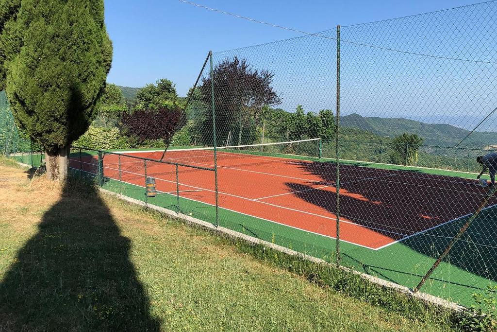 un court de tennis avec une clôture et un filet dans l'établissement Villa La Chiesina - Happy Rentals, à Arcidosso