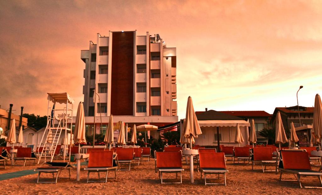 - un groupe de chaises et de parasols devant un hôtel dans l'établissement Hotel Ambassador, à Marotta
