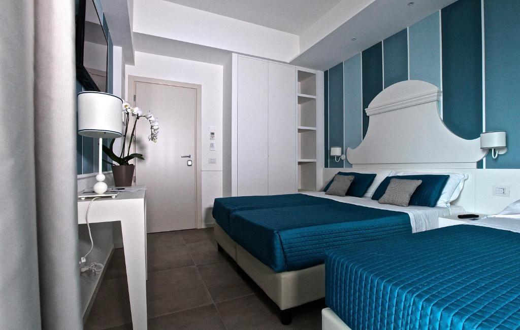 - une chambre bleue et blanche avec un lit et un bureau dans l'établissement Hotel Ambassador, à Marotta