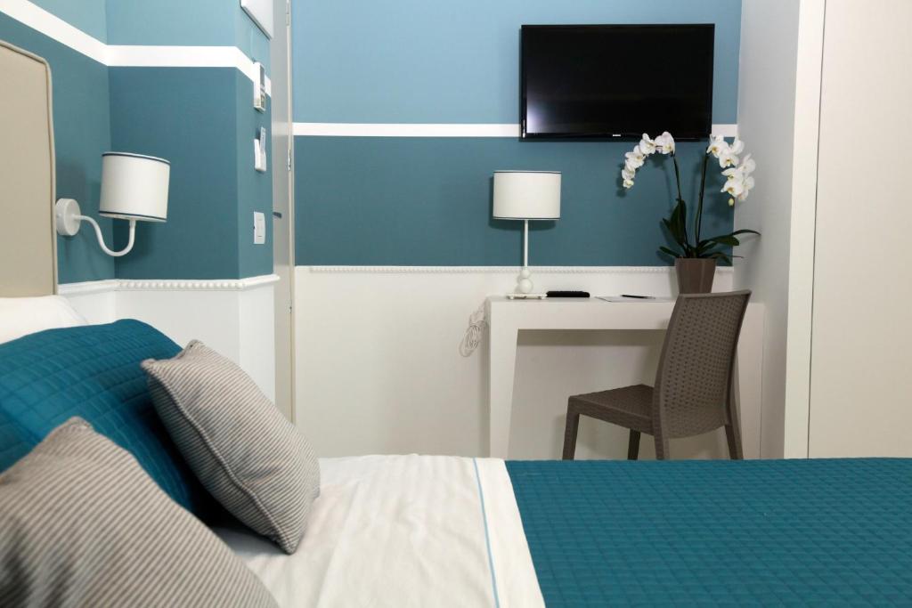 une chambre avec un lit et un bureau avec une télévision dans l'établissement Hotel Ambassador, à Marotta