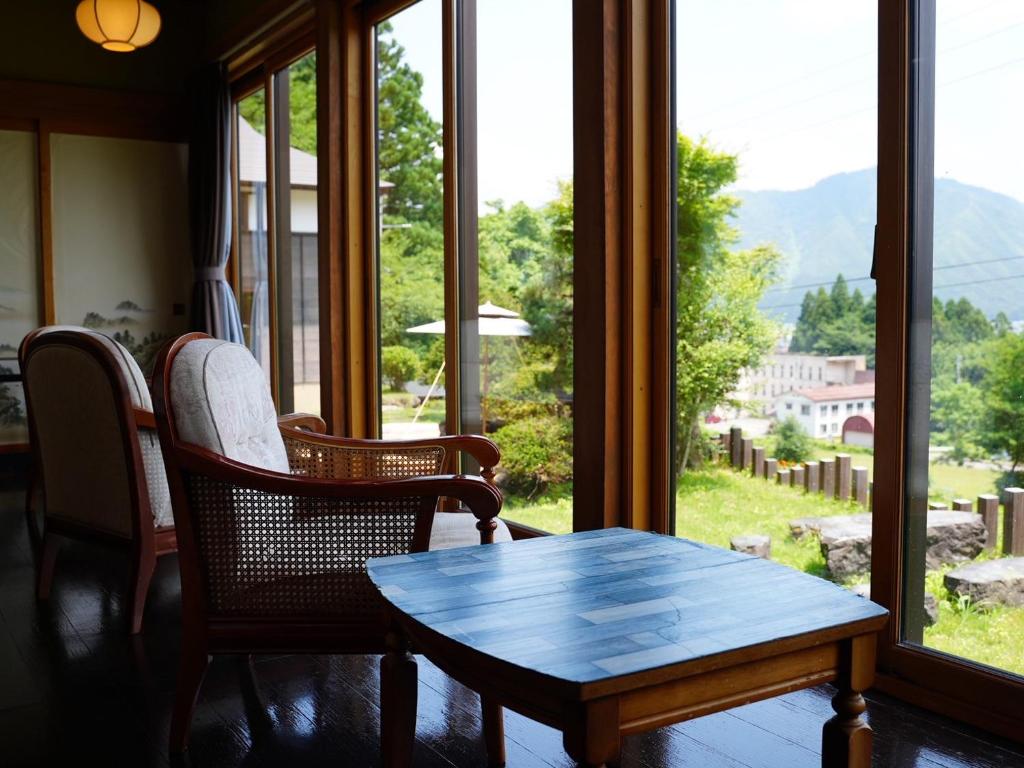 une pièce avec une table, des chaises et une fenêtre dans l'établissement Kutsurogian, à Minami Uonuma