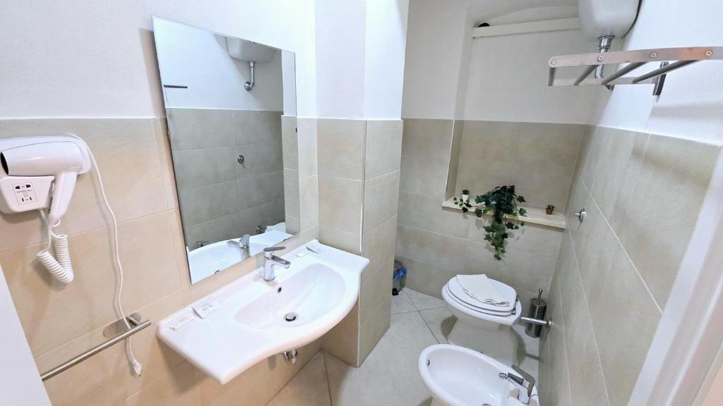 une salle de bain avec un lavabo, des toilettes et un miroir dans l'établissement Hotel paradiso, à Scalea