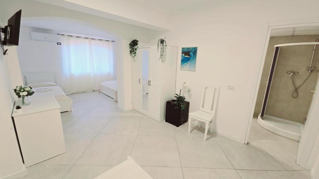 La grande salle de bains blanche est pourvue d'une douche et d'un lavabo. dans l'établissement Hotel paradiso, à Scalea