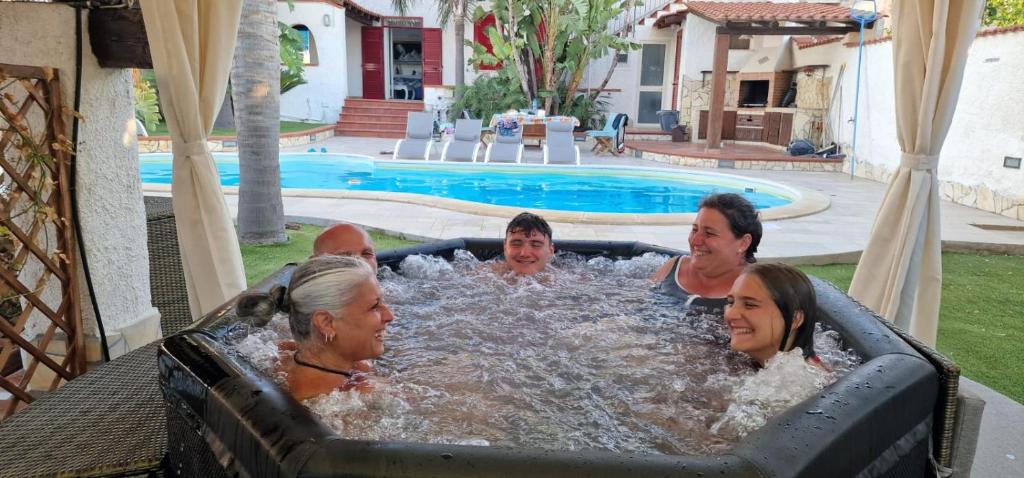 un groupe de personnes dans un jacuzzi au bord d'une piscine dans l'établissement RIFLESSI D'AZZURRO - la vacanza dei tuoi sogni, à Castelvetrano