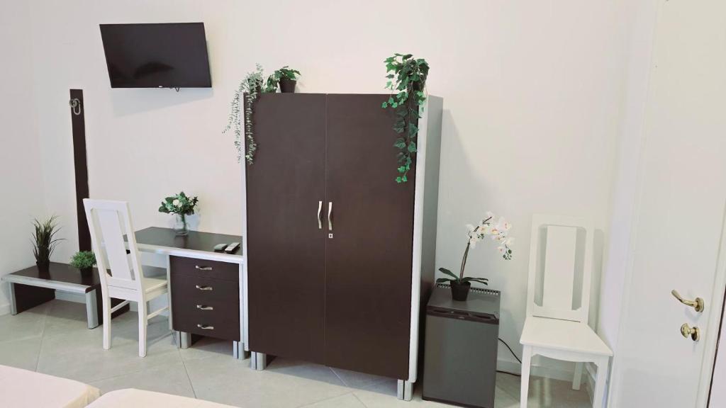 une grande armoire marron avec des plantes dessus à côté d'un bureau dans l'établissement Hotel paradiso, à Scalea