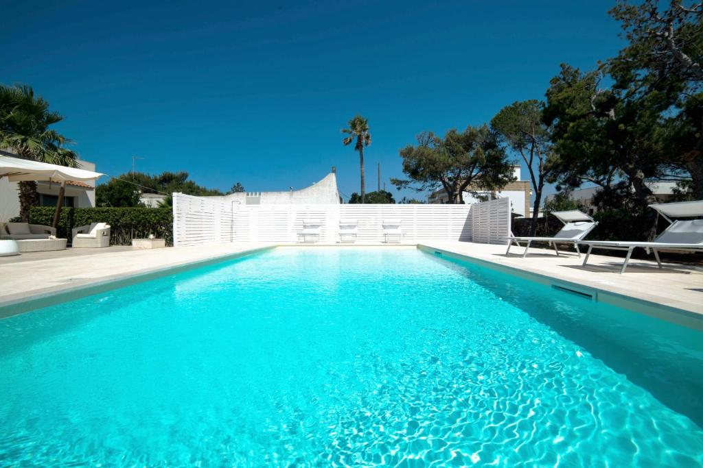 une piscine d'eau bleue en face d'une clôture blanche dans l'établissement Villa Sapore Di Sale, à Alliste
