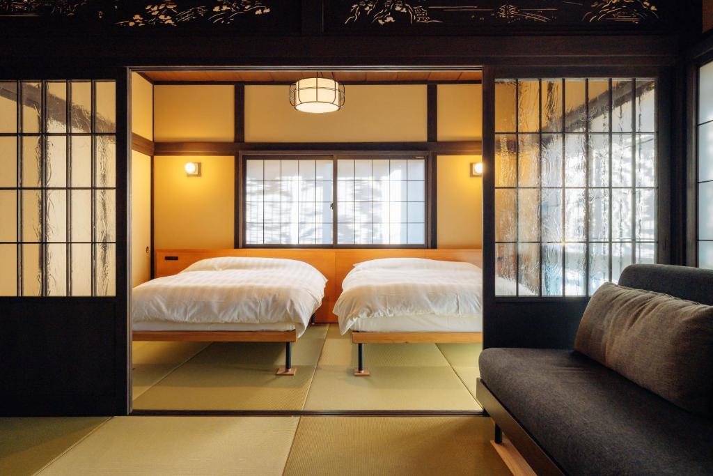 une chambre avec deux lits et un canapé dans l'établissement Hotel Hanakoyado, à Kobe