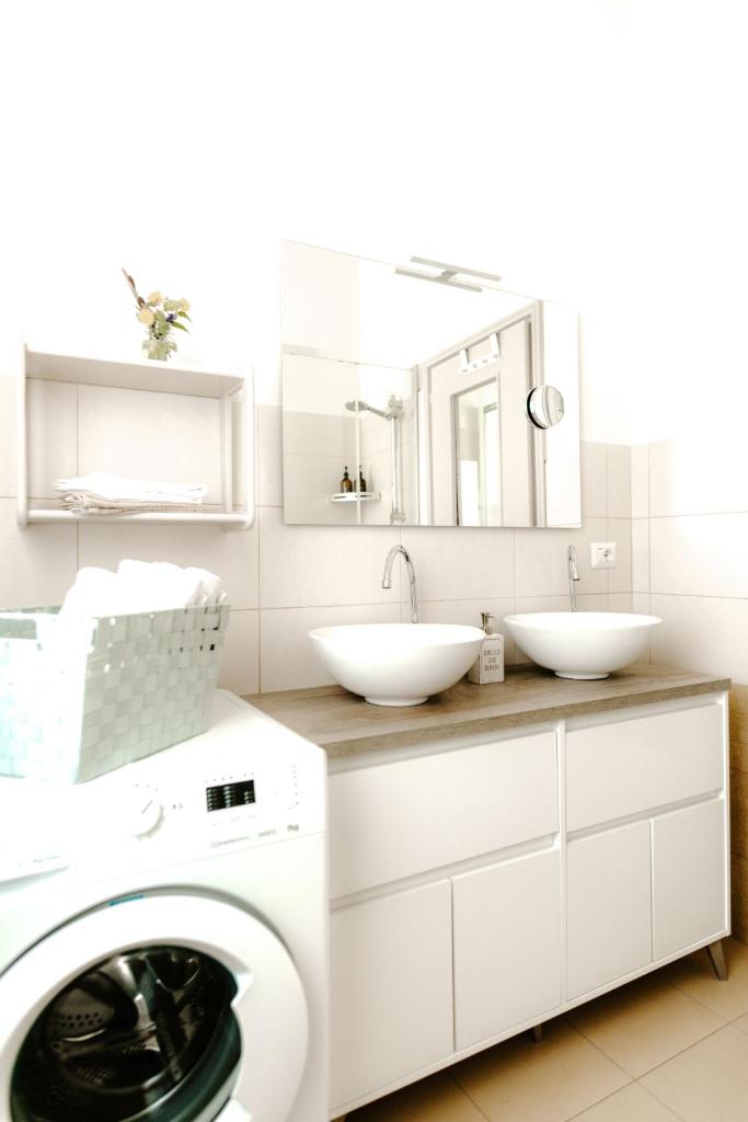 une salle de bain avec deux lavabos et une machine à laver dans l'établissement Casa Piero, relax e piscina privata tra le colline delle Langhe, à Alba