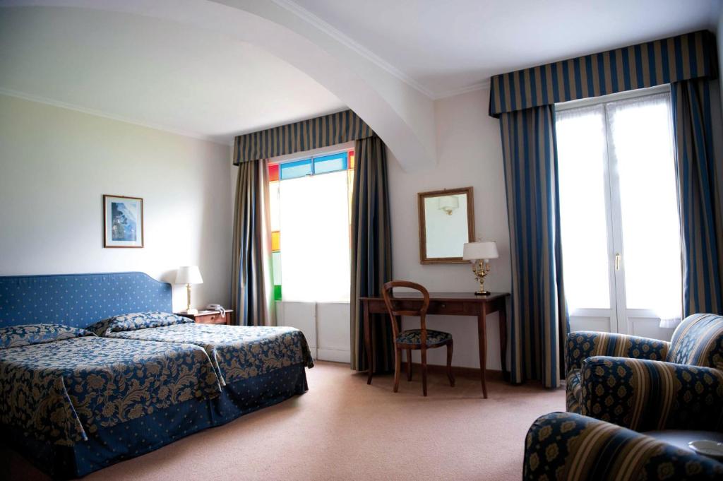 une chambre d'hôtel avec un lit, une chaise et des fenêtres dans l'établissement Hotel Stella D'Italia, à Valsolda