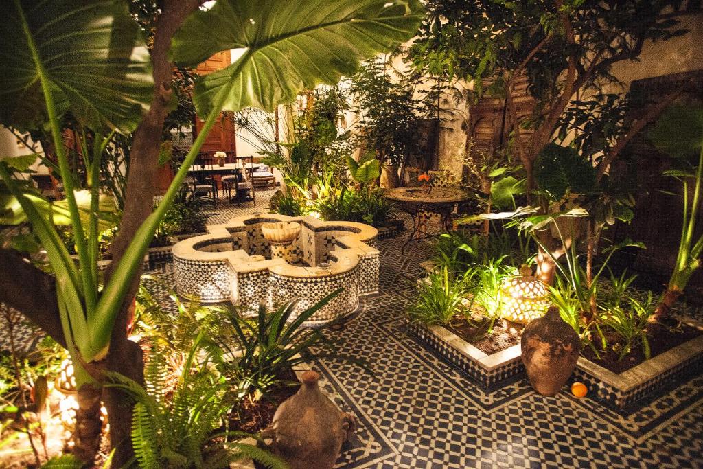 un jardin avec une fontaine et des plantes sur un sol carrelé dans l'établissement Riad Lune et Soleil, à Fès