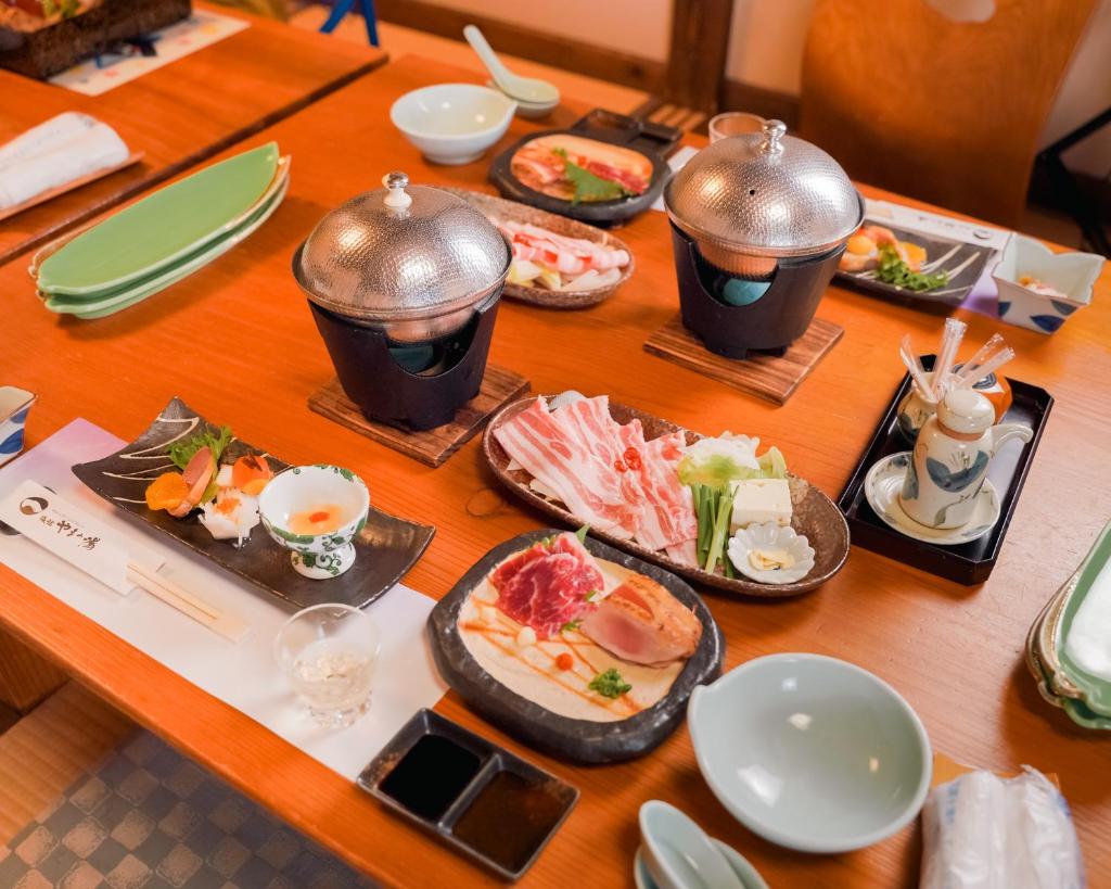 une table en bois avec des assiettes de nourriture dessus dans l'établissement Ryokan Yamanoyu, à Minamioguni