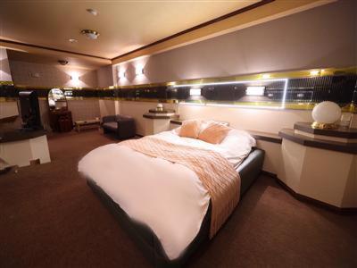 une chambre avec un grand lit dans une pièce dans l'établissement ホテルピースプラス, à Kamisu