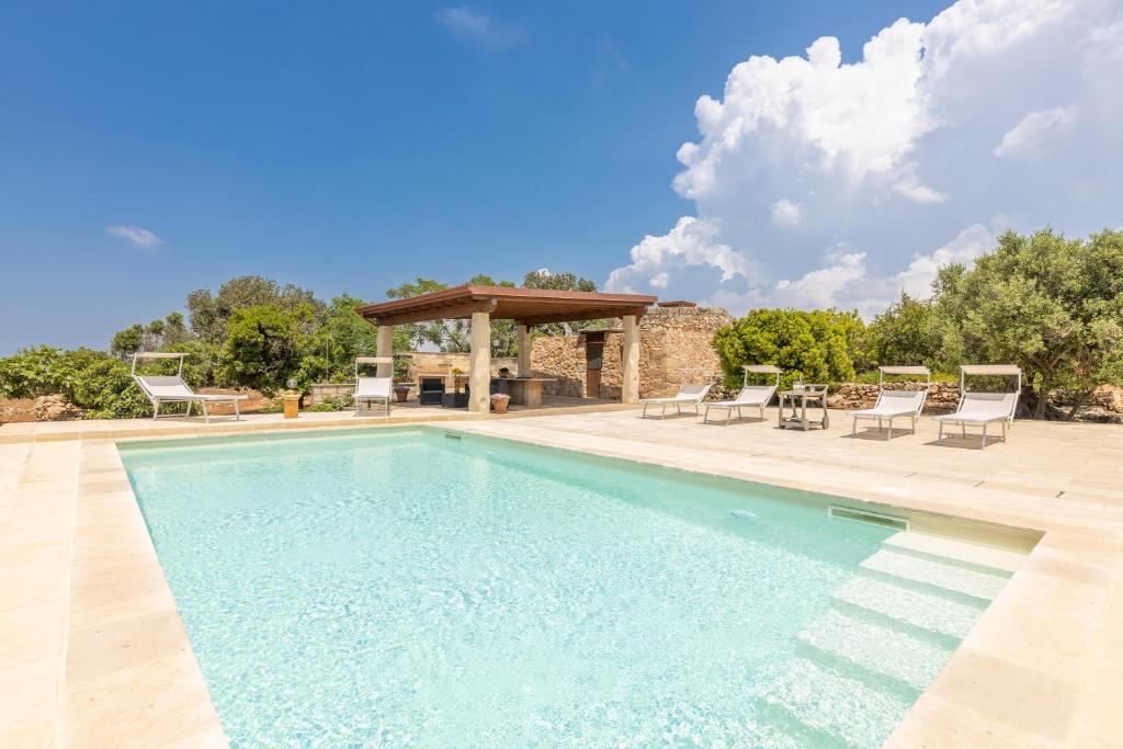 une piscine avec des chaises et un gazebo dans l'établissement Trullo la Ficarigna, à Alliste