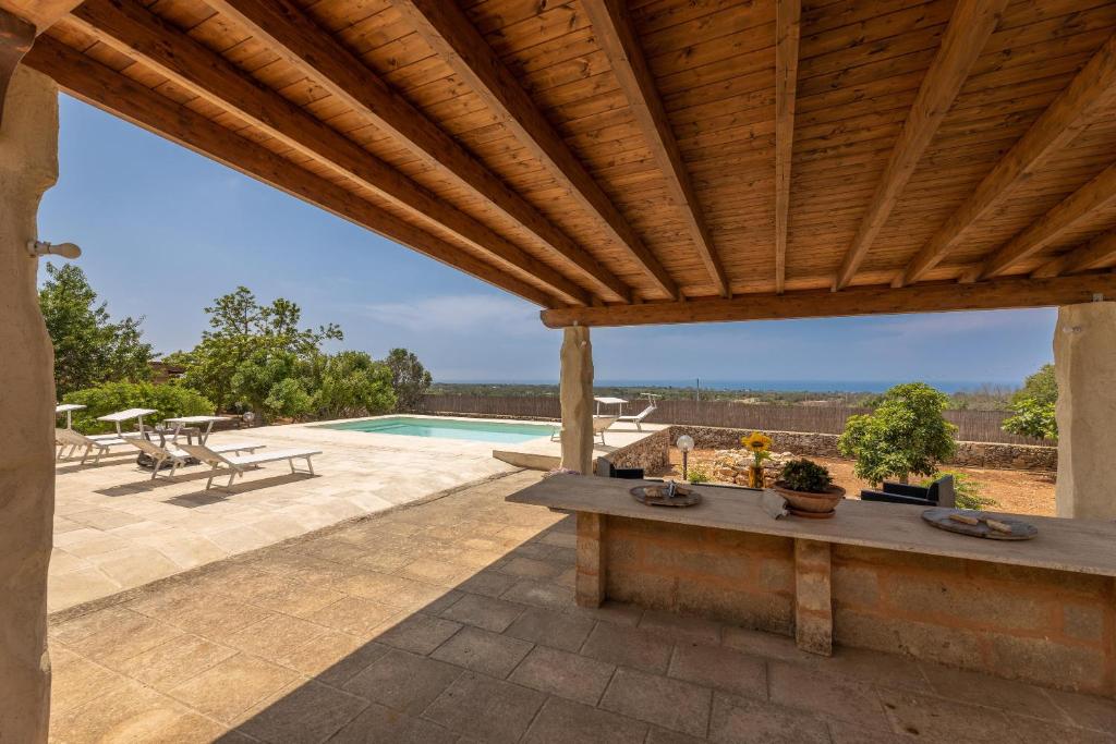 une terrasse avec une pergola en bois et une piscine dans l'établissement Trullo la Ficarigna, à Alliste