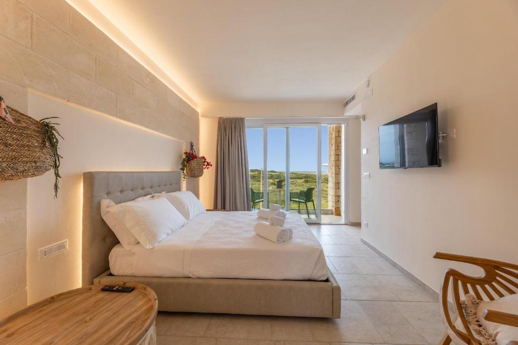 - une chambre avec un lit, une télévision et un balcon dans l'établissement Villa Regina Sul Mare, à Torre Santa Sabina