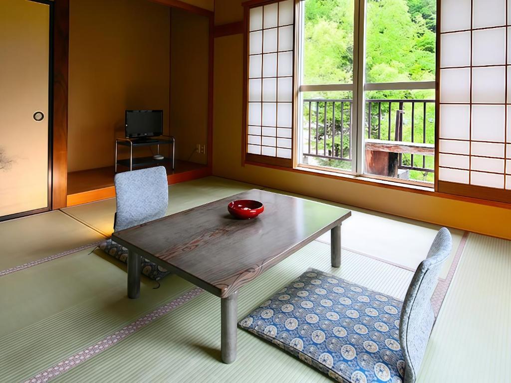 - une salle à manger avec une table en bois et 2 chaises dans l'établissement Yama no Yado Meiji Onsen, à Chino