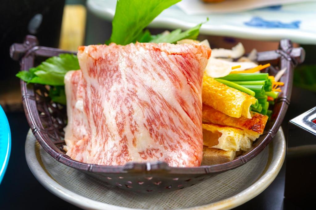 un bol rempli de viande et de légumes sur une table dans l'établissement Niseko Hot Spring Ikoino Yuyado Iroha, à Niseko