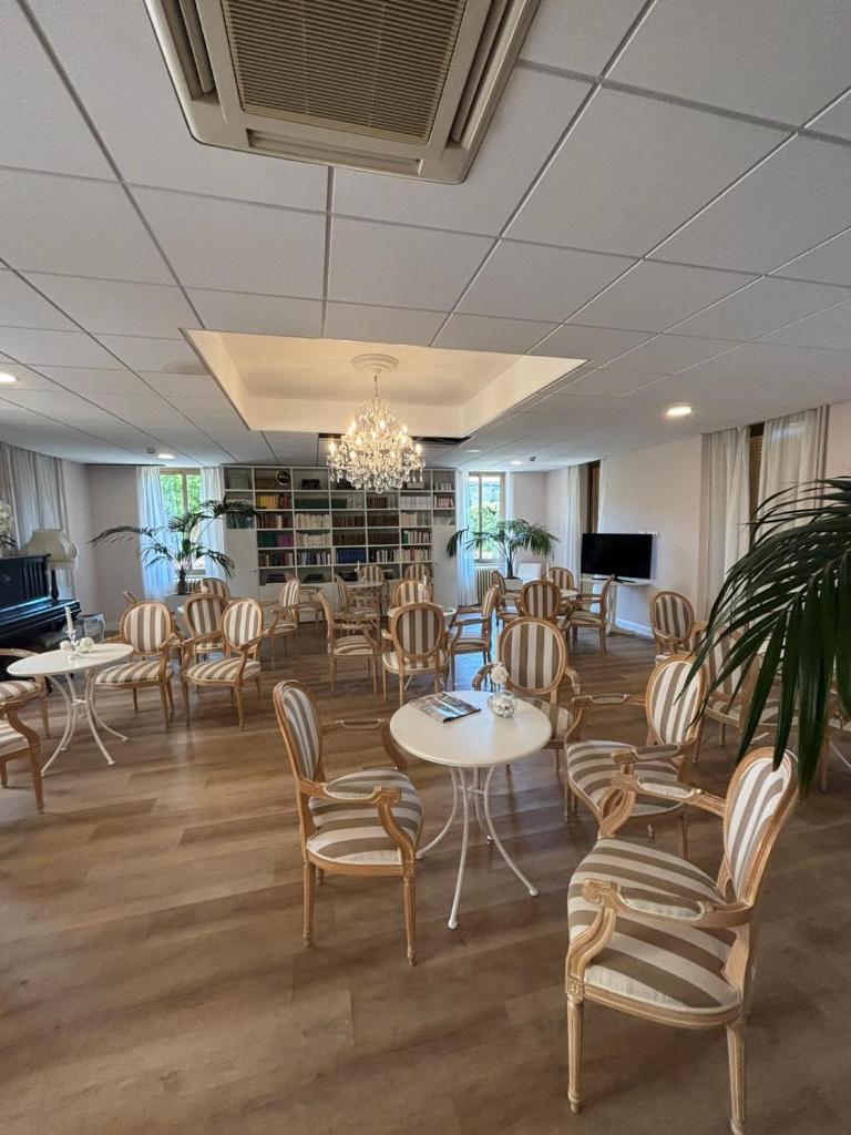 une salle d'attente avec des tables, des chaises et un piano dans l'établissement Hotel Villa Paolina, à Pietra Ligure