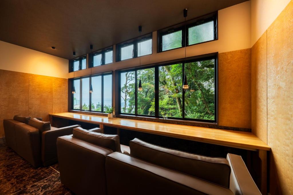 une salle d'attente avec des chaises et de grandes fenêtres dans l'établissement Umine Annex, à Beppu