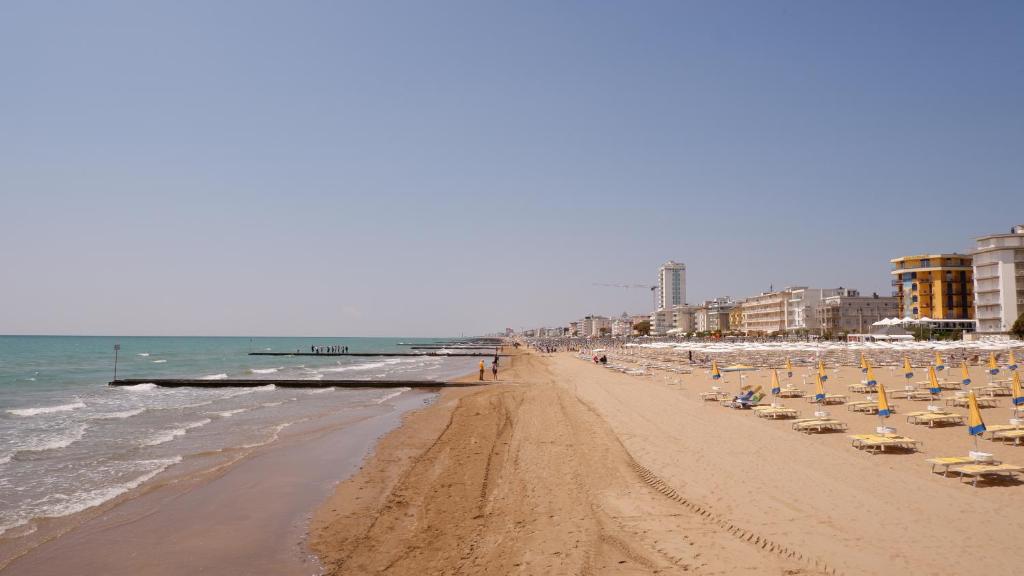 une plage avec des chaises et des parasols et l'océan dans l'établissement Hotel Venezuela, à Lido di Jesolo
