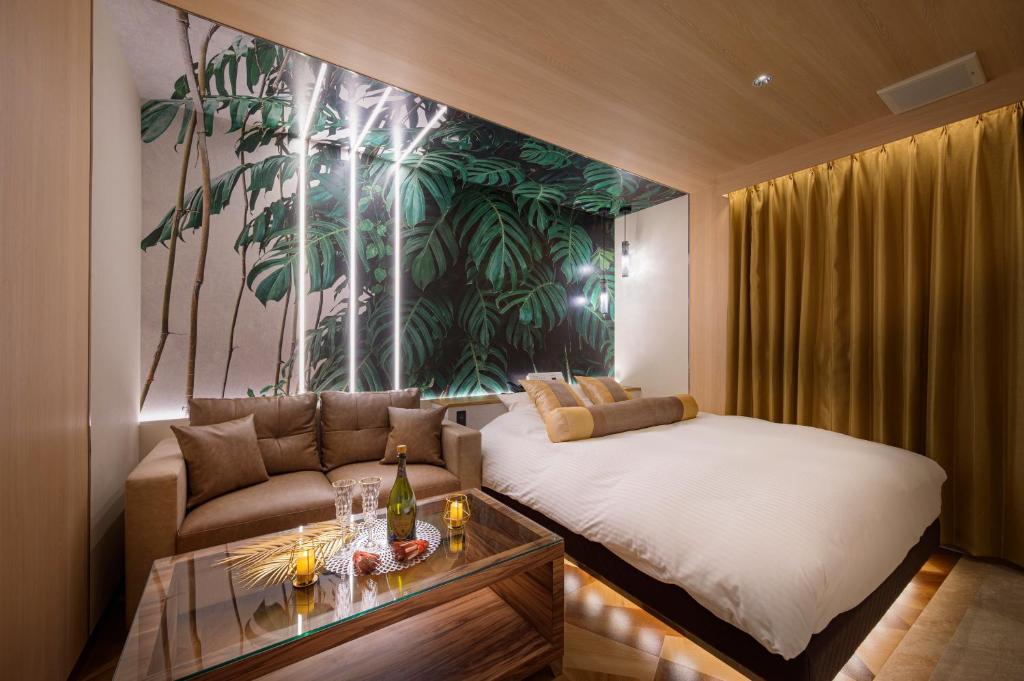 Cette chambre comprend un lit, un canapé et une table. dans l'établissement ホテルLuce Regaloｰルーチェレガーロ, à Rifu