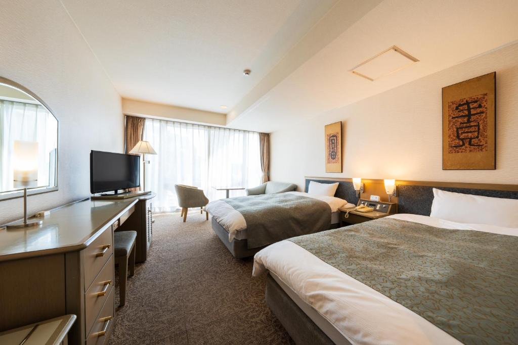 une chambre d'hôtel avec deux lits et une télévision à écran plat dans l'établissement Shiragiku, à Beppu