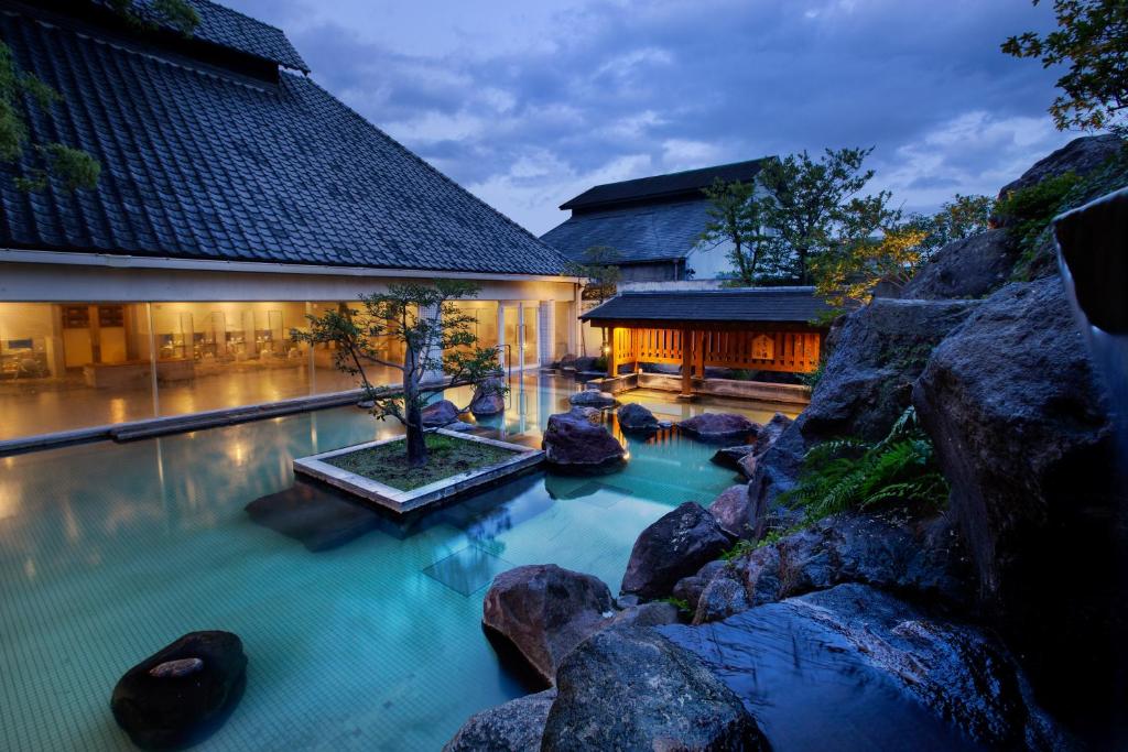 - une piscine avec des rochers en face d'un bâtiment dans l'établissement Shiragiku, à Beppu