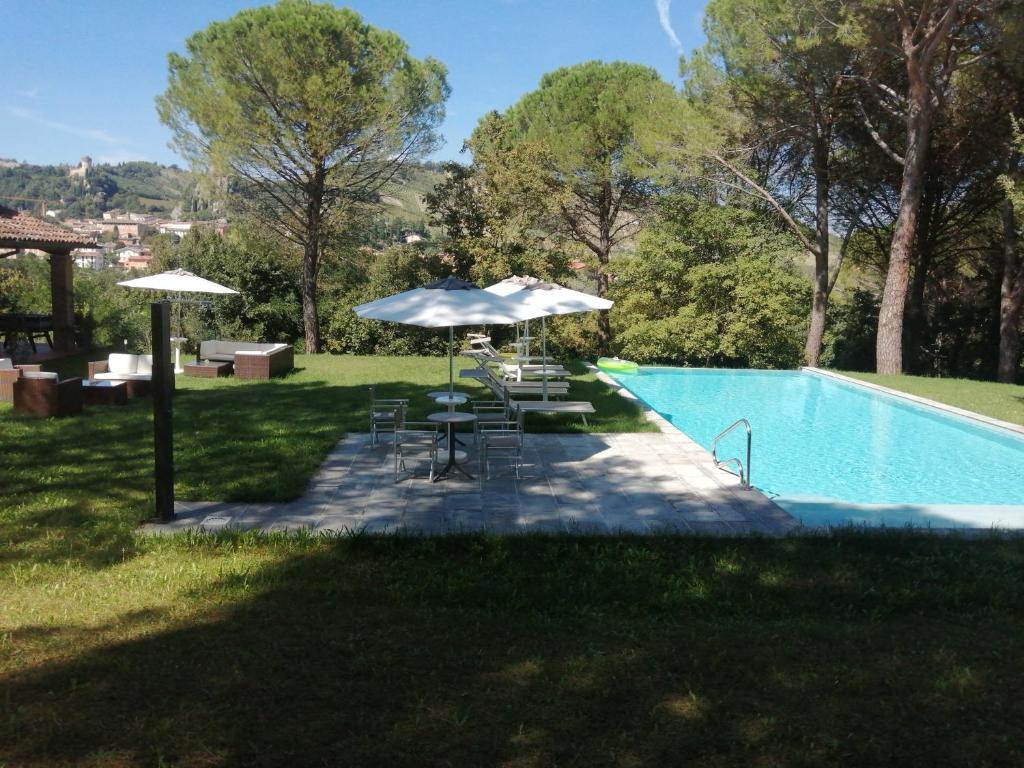 - une piscine avec des parasols, des chaises, une table et une piscine dans l'établissement Villa delle rose Brisighella, à Brisighella