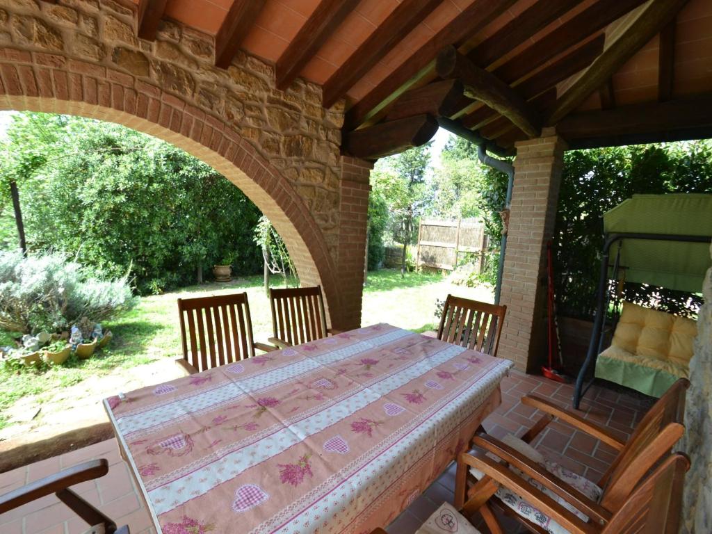 une table et des chaises sur une terrasse avec une arche dans l'établissement Villa in Suvereto with Pool and Scenic Views, à Suvereto
