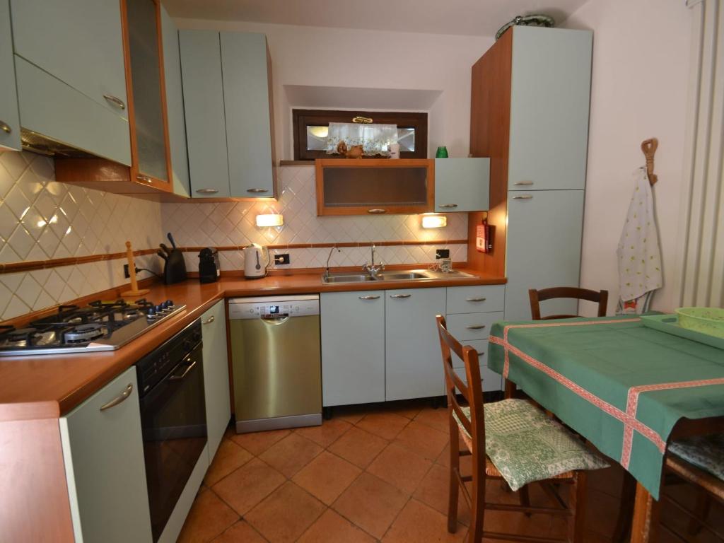 une cuisine avec des placards blancs et une table avec un tissu de table vert dans l'établissement Villa in Suvereto with Pool and Scenic Views, à Suvereto