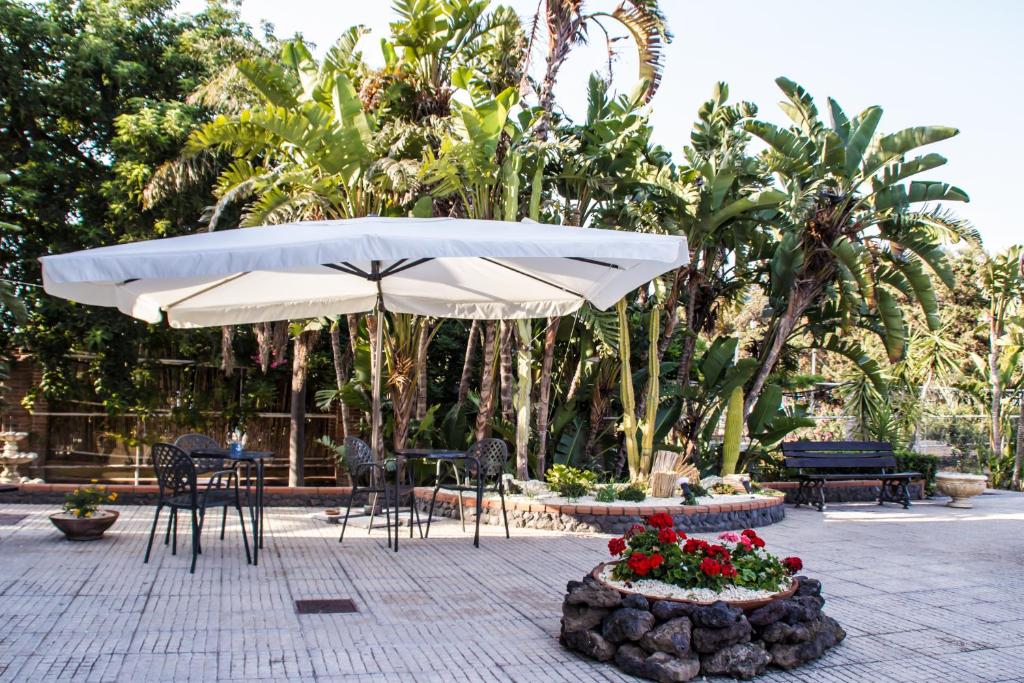 une terrasse avec un parasol, des tables et des chaises dans l'établissement Miramare Hotel, à Catane