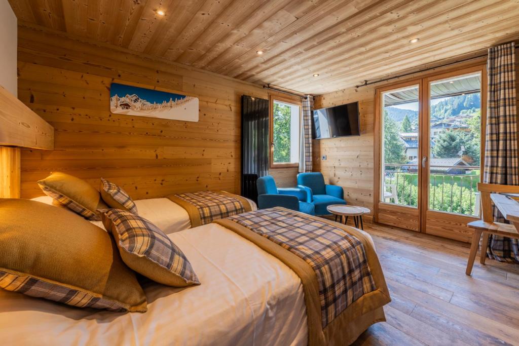 - une chambre avec 2 lits dans une pièce dotée de murs en bois dans l'établissement Hôtel Le Sporting, à Morzine