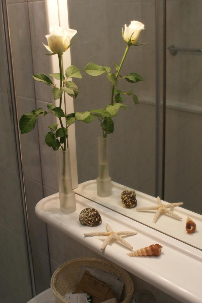 deux roses blanches en vases sur un comptoir devant un miroir dans l'établissement Hotel Michela, à Marina di Massa 99 autres photos