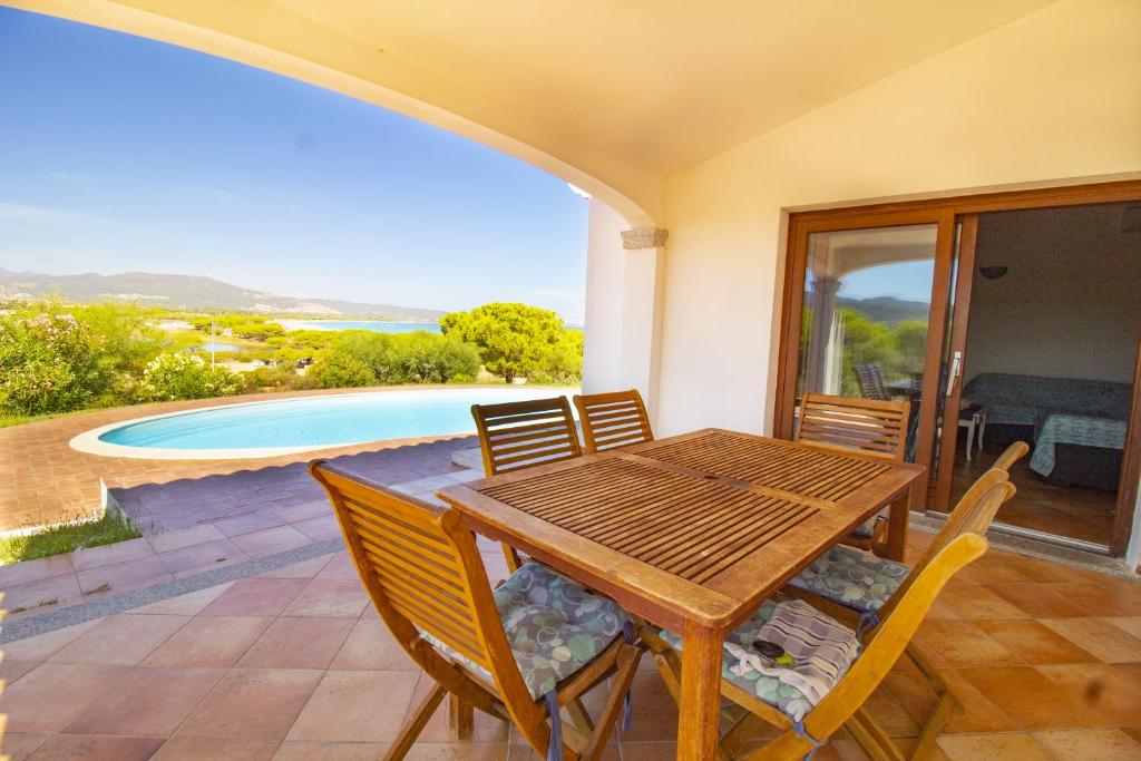 une table et des chaises en bois sur une terrasse avec une piscine dans l'établissement Villa Gallura Dream, à Budoni