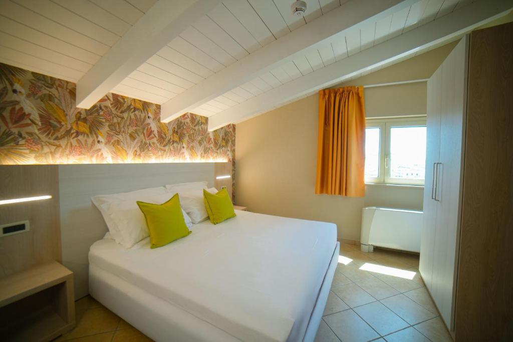 - une chambre avec un lit blanc et 2 oreillers verts dans l'établissement Hotel Prestige, à Montesilvano