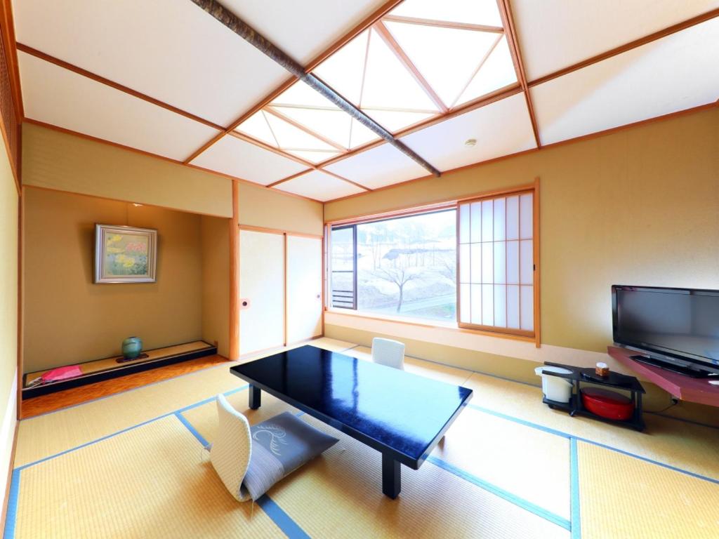 un salon avec une table et une télévision dans l'établissement Sasakura onsen Ryuunso, à Itoigawa
